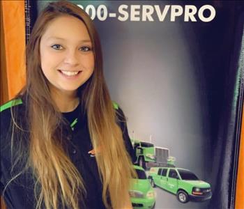 Female Production Technician Kelsey standing in front of a SERVPRO banner