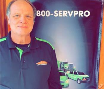 male owner of business standing in front of Green SERVPRO vehicle
