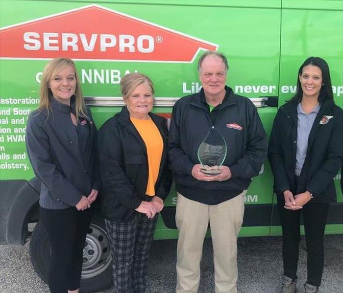 Five people standing in front of green van holding glass TORCH award